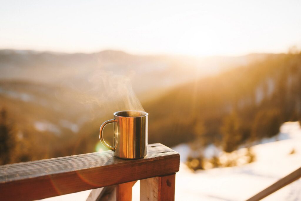 The mug of hot coffee in the winter mountains at sunrise